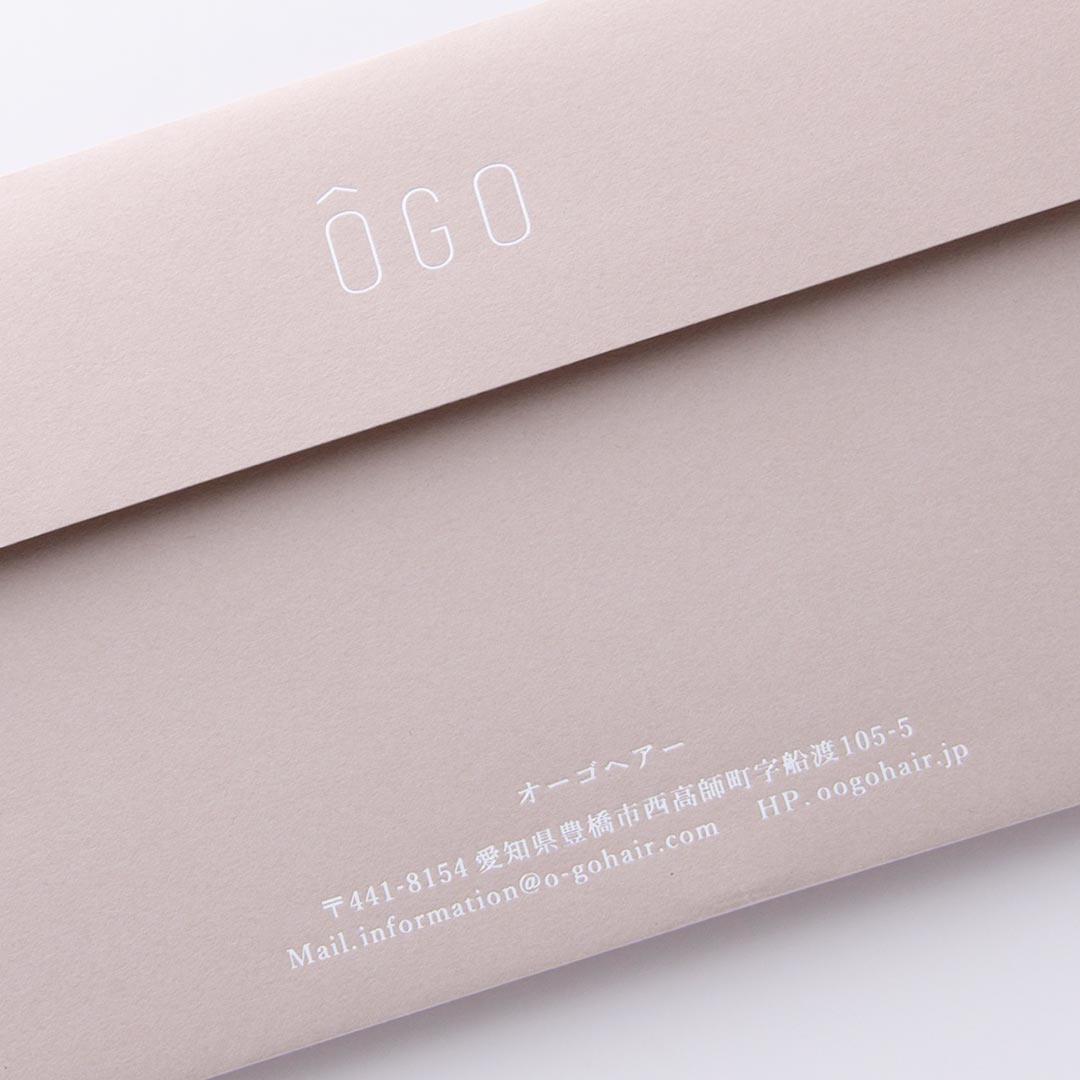 グレージュの封筒に、つや消し銀箔がさりげなく輝く美容院の特別な封筒